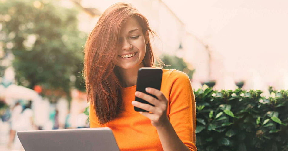 Jonge vrouw kijkt lachend naar haar smartphone