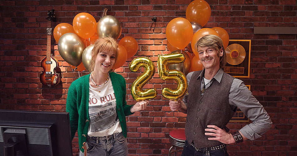 Jonge vrouw en jonge man in gitaarwinkel met 25 jaar ballon