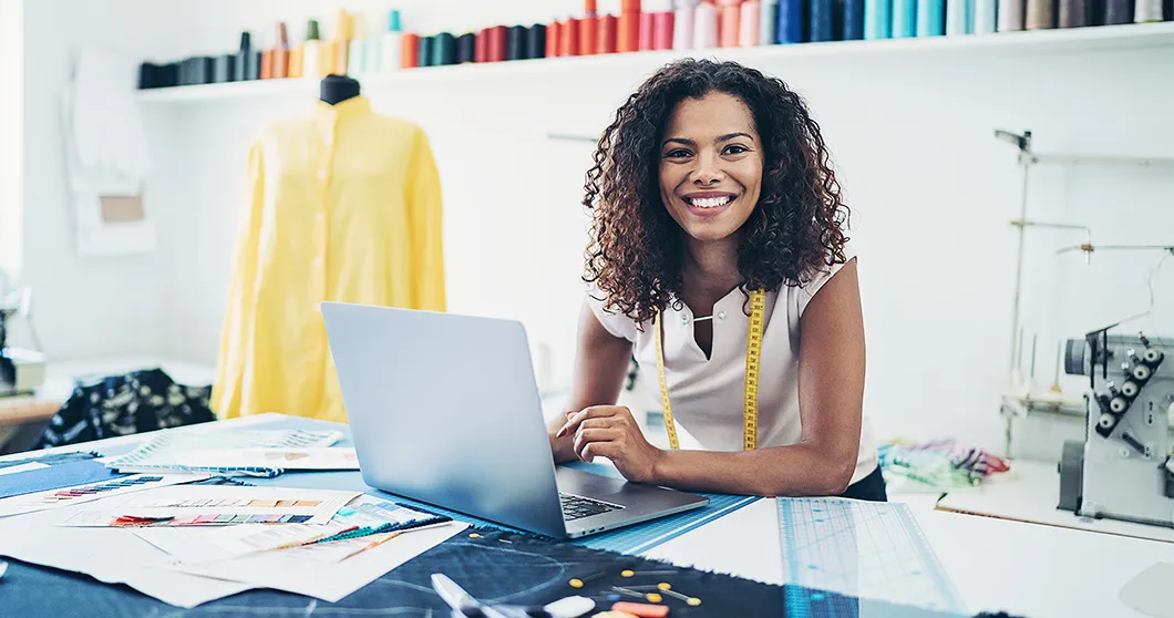Modedesigner in atelier met laptop